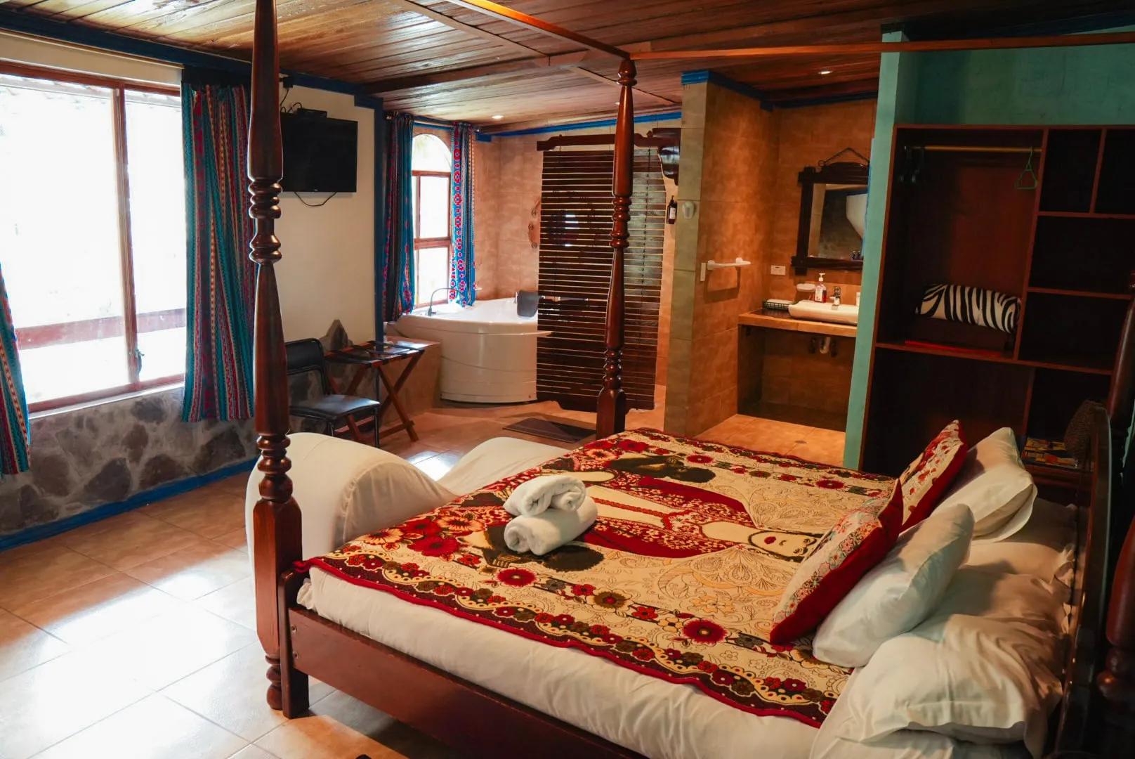 Cama de la habitación Casa Azul con textiles de Frida Kahlo y el jacuzzi al fondo