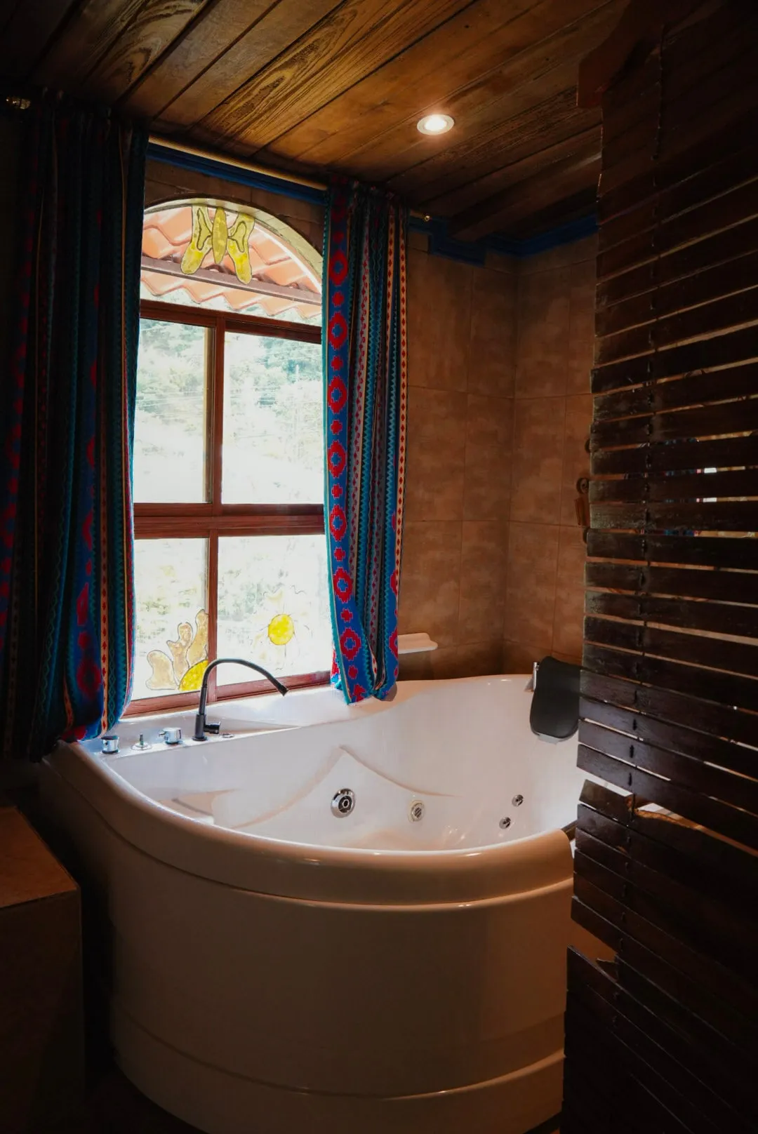 Jacuzzi de la habitación Casa Azul junto a una ventana de arco con cortinas de colores