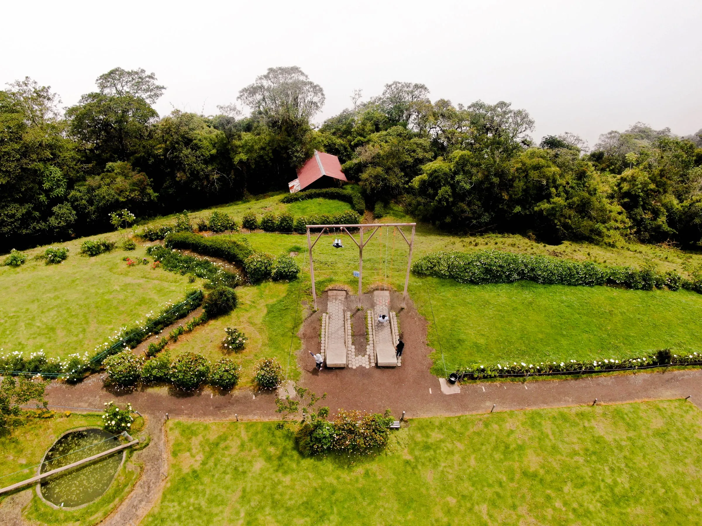 Jardines de Hotel Spa Miramelindo vistos desde el aire, con columpios, setos de rosas y el bosque de Baños de fondo
